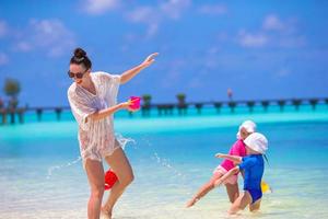 jong mam en weinig meisjes hebben pret gedurende zomer strand vakantie foto