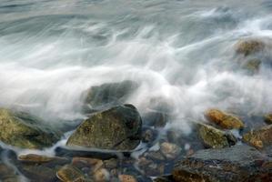 turbulentie zeewater en rots aan de kust foto