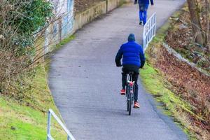 mensen zijn rijden de fiets Aan een landelijk weg Bij zonsondergang langs Donau rivier- in Regensburg, duitsland, Europa. foto