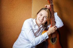 jong hipster vrouw zittend Aan verdieping en spelen gitaar Bij huis. tiener meisje aan het leren naar Speel lied en schrijven muziek- in haar kamer. hobby, levensstijl, kom tot rust, instrument, vrije tijd, onderwijs concept. foto