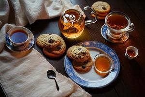 fotografie van een bord van koekjes en een glas van thee Aan een tafel met een kleding en een servet Aan het foto