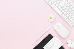 minimaal bureau tafelblad met toetsenbordcomputer, muis, witte pen, monsterablad, katoenen bloemen, bril op een roze tafel met kopie ruimte, foto
