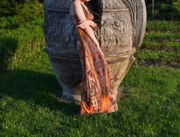 mooi brunette model- met lang haar- is hebben een foto het schieten in de park. de vrouw is vervelend een oranje lang zomer jurk