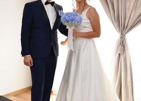 bruid en bruidegom samen Holding een blauw bloem boeket foto