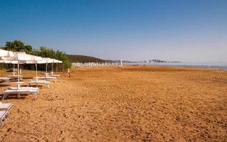 spiaggia di portuovo strand, een zanderig zonsopkomst strand en in achtergrond Aan kalkachtig rotsen de oude stad van vieste en de monoliet pizzomunno, gargaan, Italië foto