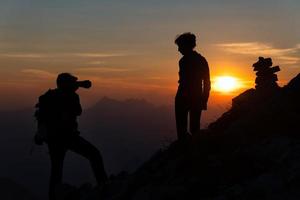 fotograaf presteert fotografie naar een meisje Bij zonsondergang in hoog bergen in silhouetten foto