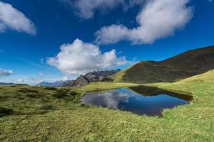 klein berg meer in de midden- van weiden foto