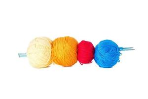 vier ballen van gekleurde wol spies door breiwerk naalden. foto