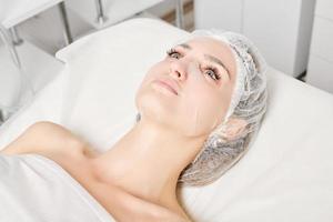 jong vrouw in vel masker Aan gezicht voor rehydrateren gezicht huid, anti rimpels procedure in schoonheid salon foto