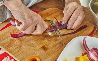 chef bezuinigingen plakjes van wortels van drie kleuren in de keuken Aan houten bord foto