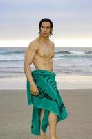 naakt Californië surfer met alleen maar een handdoek omhulsel hem is komt eraan uit van de oceaan naar droog uit. foto