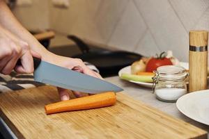 vrouw hakken wortel in keuken, dichtbij omhoog foto