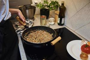 vrouw Koken saus bolognese in keuken foto