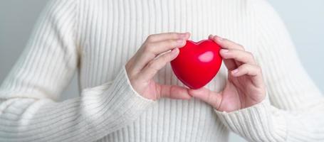 vrouw hand- Holding rood hart vorm geven aan. liefde, schenker, wereld hart dag, wereld Gezondheid dag en verzekering concepten foto