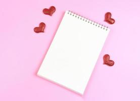 vlak leggen van geopend notitieboekje met rood schitteren harten Aan roze achtergrond met kopiëren ruimte. liefde, Valentijnsdag dag, geheugen. foto