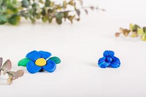 blauw bloemen van polymeer klei Aan een licht achtergrond. handgemaakt decor. kopiëren ruimte foto