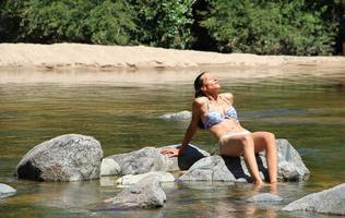 mooi jong vrouw zonnen Aan de rotsen van de berg rivier- foto