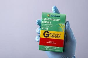 rio, Brazilië - januari 27, 2023, hand- met beschermend rubber handschoen Holding geneeskunde doos, rosuvastatine calcium foto