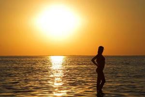 silhouet van de jong vrouw Aan een zee baai Aan een zonsondergang foto