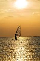 silhouet van een windsurfer Aan een zonsondergang foto