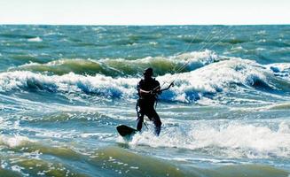 silhouet van een kitesurfer Aan golven van een zee foto