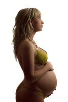 zwanger jong vrouw in geel lingerie foto
