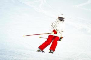 alpine ski. skiën vrouw skiër gaan bergafwaarts tegen sneeuw gedekt geïsoleerd wit ski spoor helling piste in winter. mooi zo recreatief vrouw skiër in wit ski jasje en rood broek foto