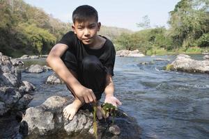 Aziatisch jongens zijn uitgeven hun vrije tijd door duiken, zwemmen, het werpen rotsen en vangen vis in de rivier- samen gelukkig. hobby en geluk van kinderen concept. foto