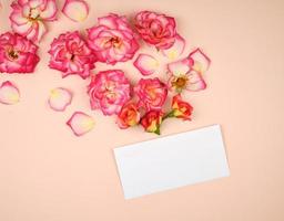 roze roos bloemknoppen en een wit papier envelop Aan een bieg achtergrond foto