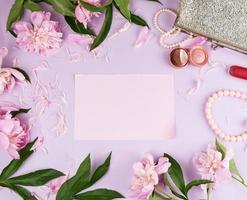 roze bladzijde, boeket van pioenrozen, rood lippenstift en een vrouw zilver koppeling foto