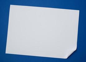 blanco wit vel van papier met een gekruld hoek Aan een blauw achtergrond foto
