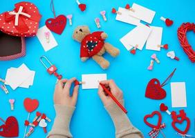 vrouw hand- houdt een rood houten potlood en schrijft Aan een wit papier bedrijf kaart, De volgende naar karton dozen foto