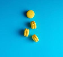 ronde geel gebakken macarons met room liggen Aan een blauw achtergrond foto