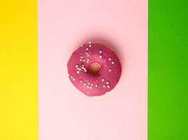 geheel ronde rood donut met hagelslag liggen Aan een kleur achtergrond foto