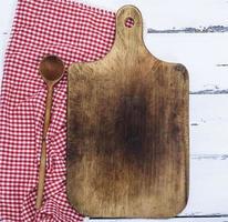 leeg bruin oud keuken snijdend bord en houten lepel foto