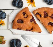 plakjes van biscuit Pruim taart Aan een wit houten bord en vers fruit foto