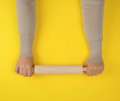 hand- Holding een houten rollend pin Aan een geel achtergrond foto