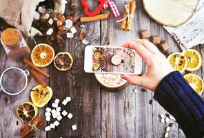 een wit smartphone in een vrouw hand- duurt een fotograaf van een mok met een drinken en stukken van heemst foto