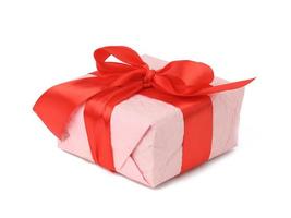 rechthoekig doos verpakt in roze papier en gebonden met een rood zijde lint Aan een wit achtergrond foto