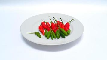 dichtbij omhoog van rauw rood en groen pepers Aan een wit bord geïsoleerd Aan wit achtergrond foto