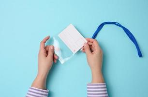 vrouw hand- houdt transparant plastic insigne Aan een blauw draagriem Aan een blauw achtergrond foto