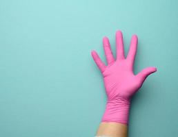 vrouw hand- in een roze latex handschoen Aan een blauw achtergrond, palm Open foto