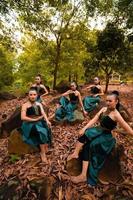 een groep van Indonesisch dansers zittend prachtig Aan de rots met bruin bladeren in de achtergrond binnen de Woud foto