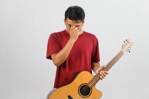 portret van jong Aziatisch Mens in rood t-shirt met een akoestisch gitaar geïsoleerd Aan wit achtergrond foto