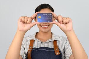 portret van jong Aziatisch vrouw in serveerster uniform houding met credit kaart foto