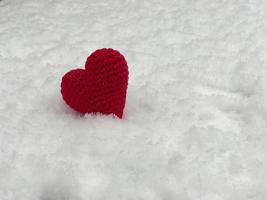 klein rood gebreid hart aan het liegen Aan de wit sneeuw foto