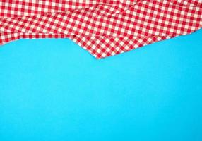 wit rood geruit keuken handdoek Aan een blauw achtergrond, helder picknick achtergrond foto