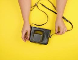 twee vrouw handen zijn Holding een oud film camera in een bruin leer geval foto