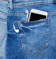 wit smartphone met hoofdtelefoons in de terug zak- van blauw jeans foto