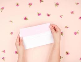 vrouw handen Open wit papier envelop, in de midden- een brief Aan roze papier foto